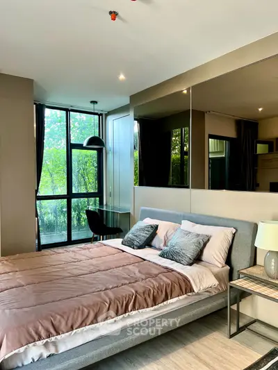 Modern bedroom with large windows and stylish decor in a serene setting.