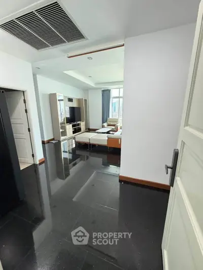 Spacious modern living room with sleek black flooring and stylish furniture, perfect for relaxation and entertainment.