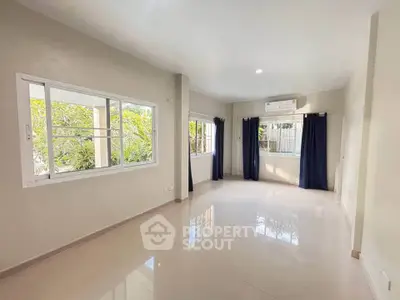 Spacious living room with large windows and natural light in modern home.