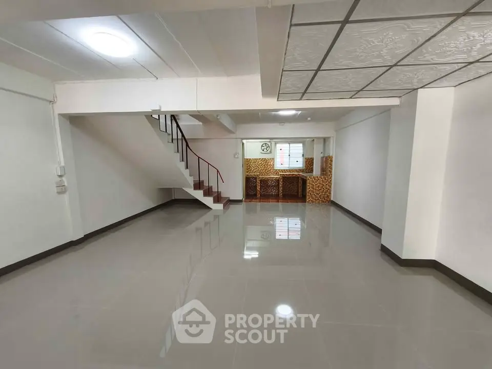 Spacious open-plan living area with modern tiled flooring and staircase, ideal for customization.