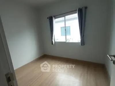 Spacious empty bedroom with wooden flooring and natural light