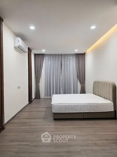 Spacious minimalist bedroom with elegant curtains and modern lighting, perfect for serene living.