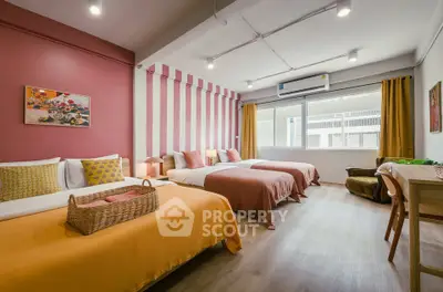 Spacious bedroom with vibrant decor and large window for natural light