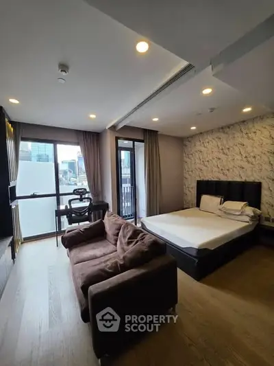 Modern studio apartment with city view, featuring cozy bed, stylish sofa, and workspace area.