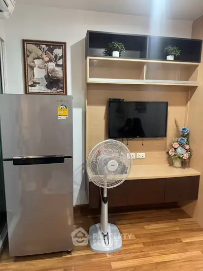 Modern living room with sleek fridge, wall-mounted TV, and stylish decor in cozy apartment.