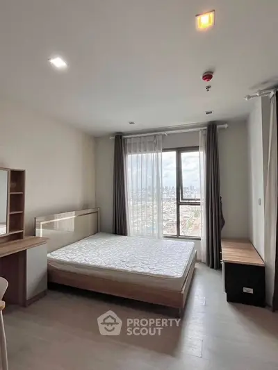 Spacious bedroom with city view and modern furnishings in high-rise apartment.