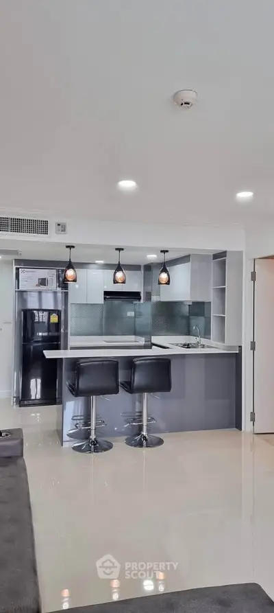 Modern kitchen with sleek design, featuring an open layout and stylish bar stools, perfect for contemporary living.
