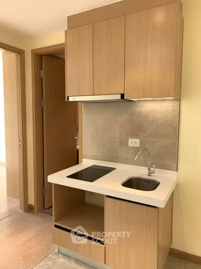 Modern compact kitchen with sleek wooden cabinets and built-in electric stove