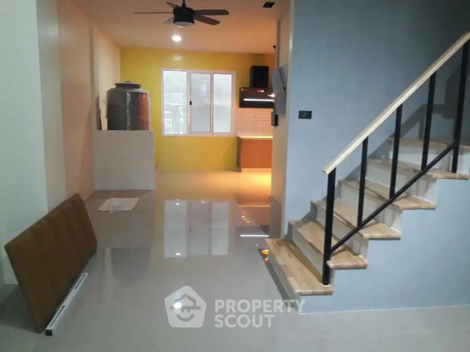 Modern open-plan living area with sleek staircase and bright kitchen