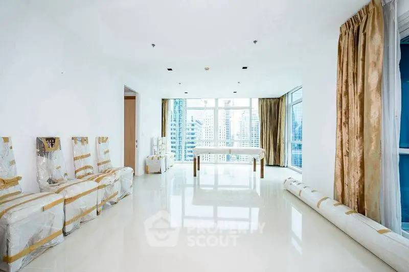 Spacious modern living room with floor-to-ceiling windows and city skyline view.