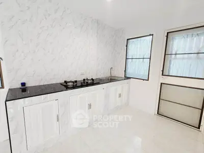 Modern kitchen with sleek white cabinetry and gas stove in bright, airy space.