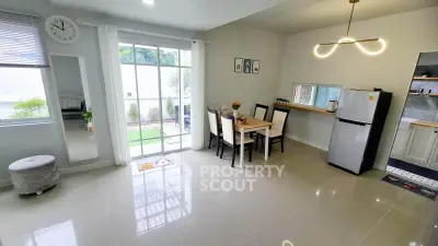 Modern open-plan living and dining area with garden view and sleek kitchen appliances.