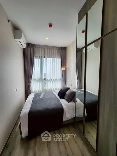 Modern bedroom with stylish decor, large mirrored wardrobe, and natural light from window.