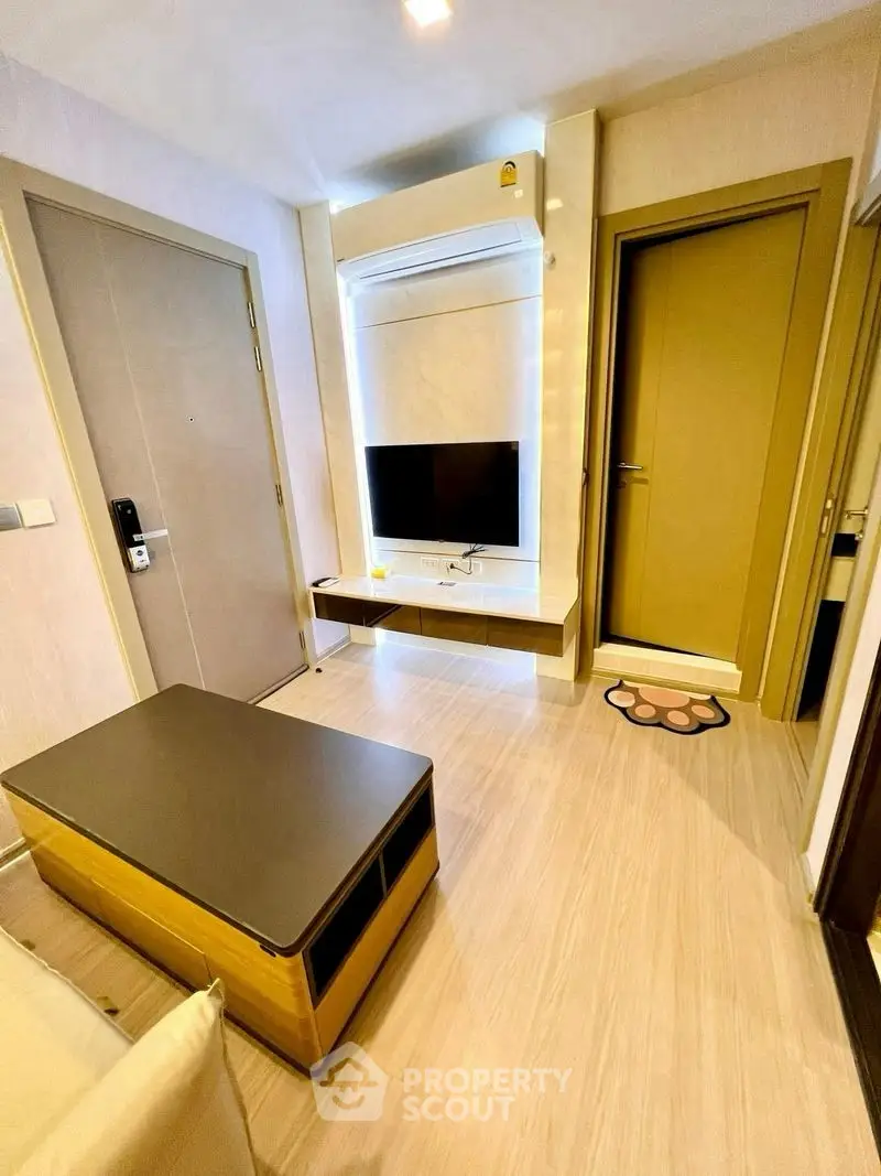 Modern living room with sleek furniture and wall-mounted TV in a cozy apartment.