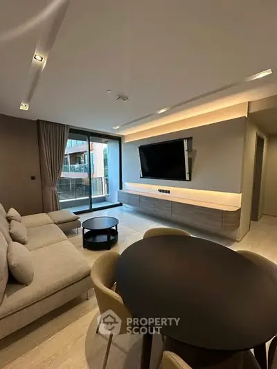 Modern living room with sleek furniture and large TV, featuring a spacious layout and balcony view.