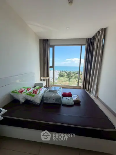 Spacious bedroom with large window offering stunning cityscape views, perfect for relaxation and comfort.