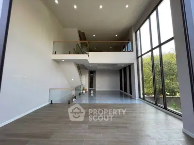 Stunning modern living room with high ceilings and expansive windows offering natural light and garden views.