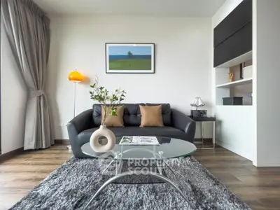 Modern living room with stylish decor, featuring a black leather sofa, glass coffee table, and elegant floor lamp.