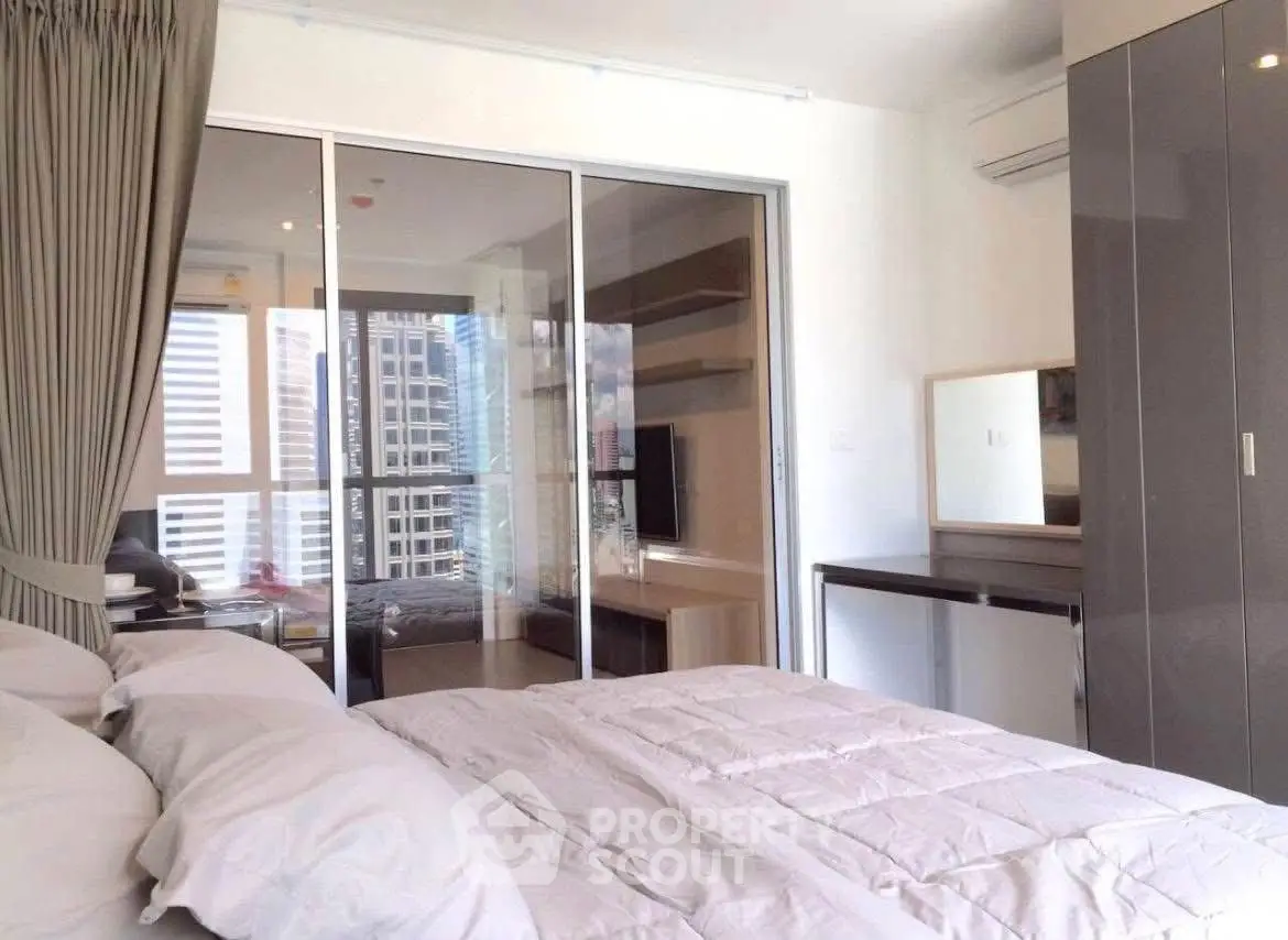 Modern bedroom with city view and sliding glass doors to a cozy study area.