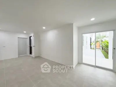 Spacious modern living room with sliding glass doors leading to a lush garden view.