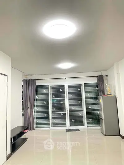 Spacious living room with modern lighting and sliding glass doors leading to a balcony.