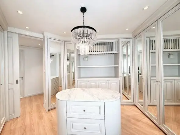 Luxurious walk-in closet with elegant chandelier and ample storage space.