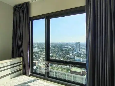 Stunning bedroom view with expansive cityscape from high-rise apartment window.