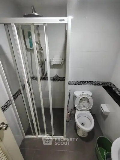 Compact bathroom with shower enclosure and modern fixtures in a real estate property.