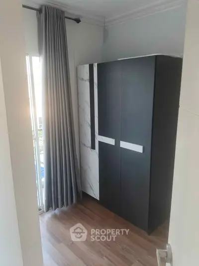 Modern bedroom with sleek wardrobe and floor-to-ceiling window with curtains.