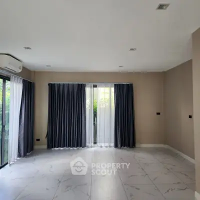Spacious empty living room with large windows and elegant curtains
