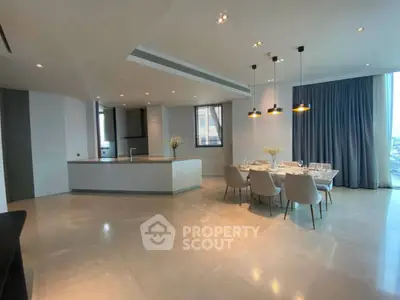 Spacious modern living room with open kitchen and elegant dining area, featuring sleek lighting and large windows.