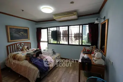 Cozy bedroom with large window and wooden flooring, featuring a bed and dresser, perfect for relaxation.