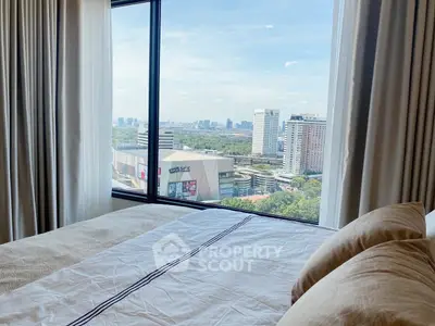 Luxurious bedroom with stunning city view from large window, featuring elegant bedding and curtains.
