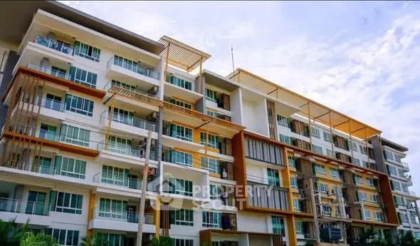Modern multi-story apartment building with large windows and balconies under a clear blue sky.