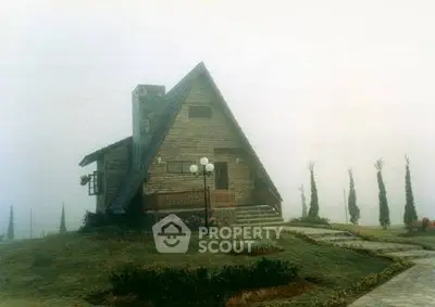 Charming A-frame cabin in misty landscape with rustic appeal and serene surroundings.