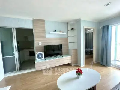 Modern living room with TV, wooden flooring, and access to bedroom and kitchen.