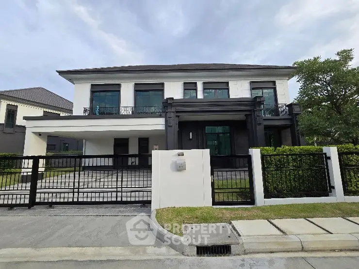 Stunning modern two-story house with sleek black and white exterior, spacious driveway, and lush greenery.