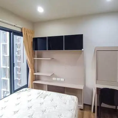 Modern bedroom with large window and built-in storage solutions.