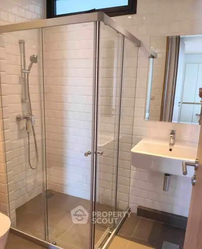 Modern bathroom with glass shower enclosure and sleek white sink.