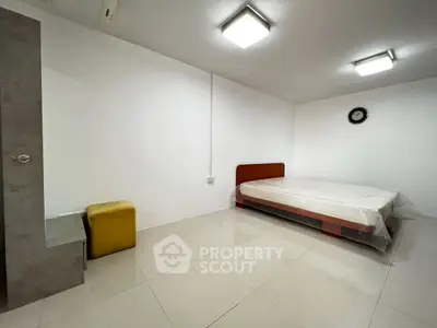 Minimalist bedroom with modern lighting and tiled flooring, featuring a bed and a small seating area.