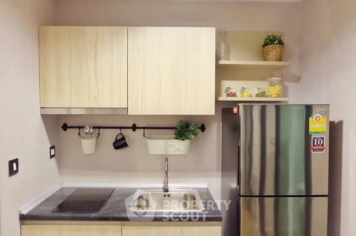 Modern kitchen with sleek cabinetry and stainless steel fridge in a compact layout.