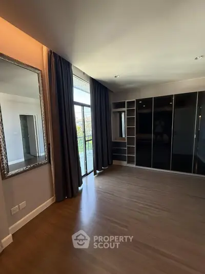 Spacious bedroom with large wardrobe and balcony access, featuring elegant wooden flooring and modern design.