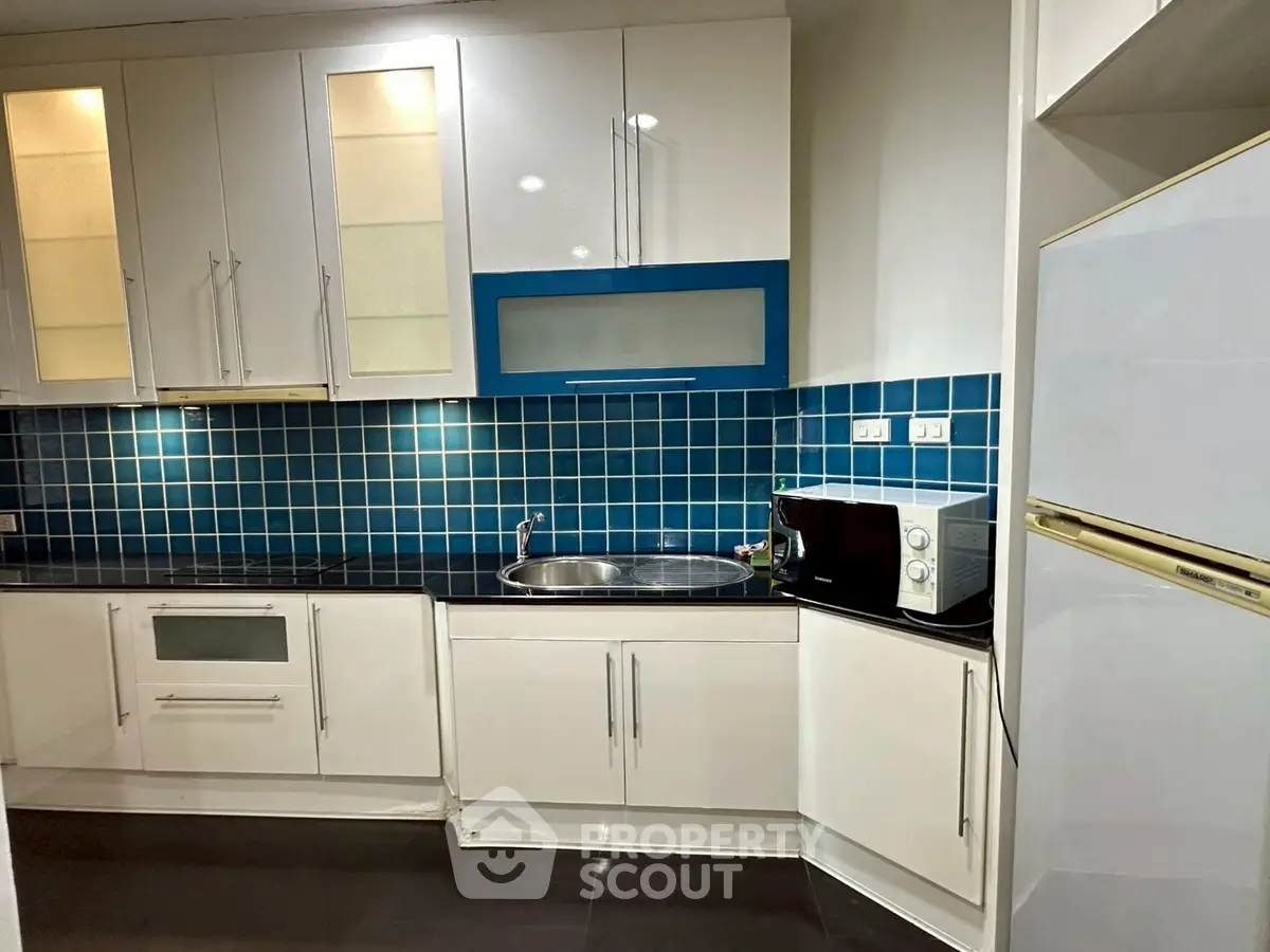 Modern kitchen with sleek white cabinets and blue tile backsplash