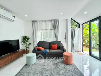 Modern living room with sleek furniture and large windows overlooking lush garden.