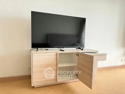 Modern living room with sleek TV stand and large flat-screen TV, showcasing minimalist interior design.