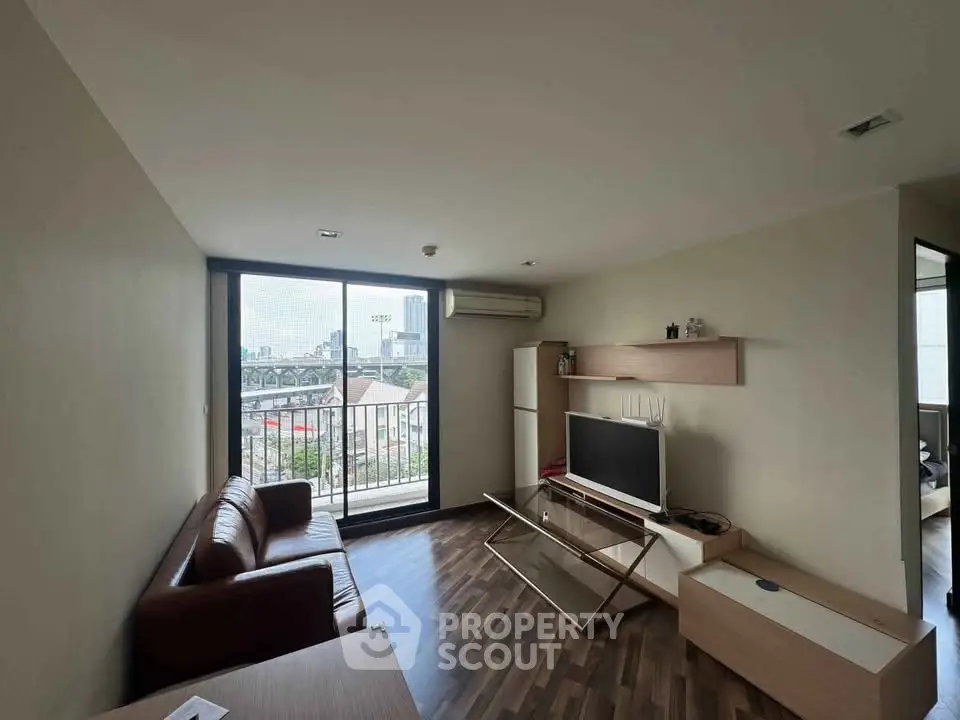 Modern living room with city view, featuring sleek furniture and large window for natural light.