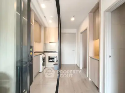 Modern kitchen with sleek appliances and wooden cabinetry in a bright apartment.