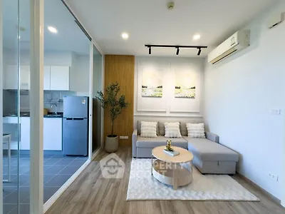 Modern living room with stylish decor and open kitchen layout, featuring cozy seating and sleek appliances.