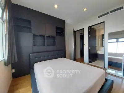 Spacious bedroom with modern design and ensuite bathroom in luxury apartment.
