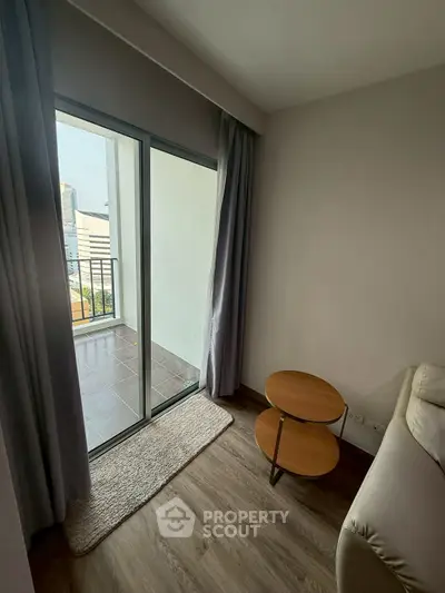 Cozy living room with balcony access and modern furnishings in urban apartment.